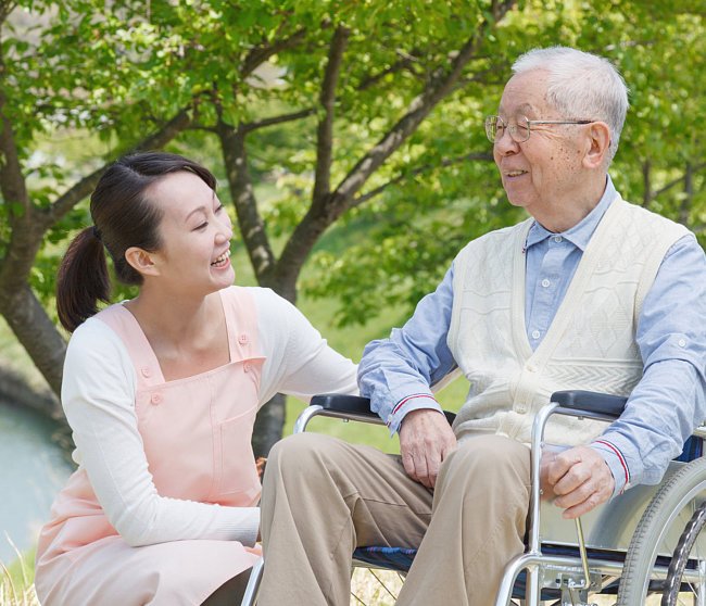 Senior sitting on a wheelchair with carer