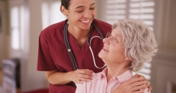 hispanic female nurse looking and smiling with an elder